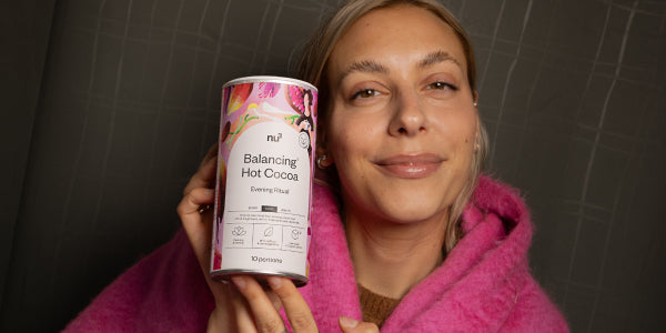 Glückliche Frau mit einer Dose nu3 Balancing Hot Cocoa