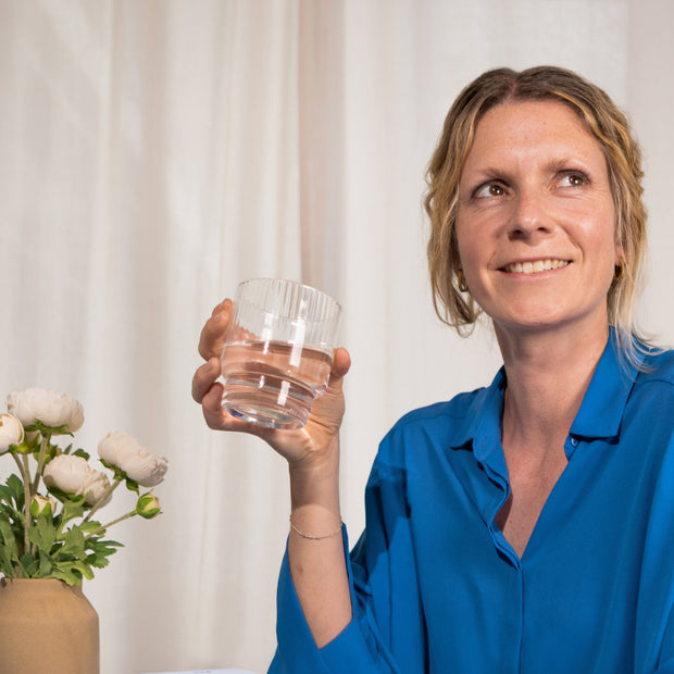 Frau, die ein Wasserglas hält
