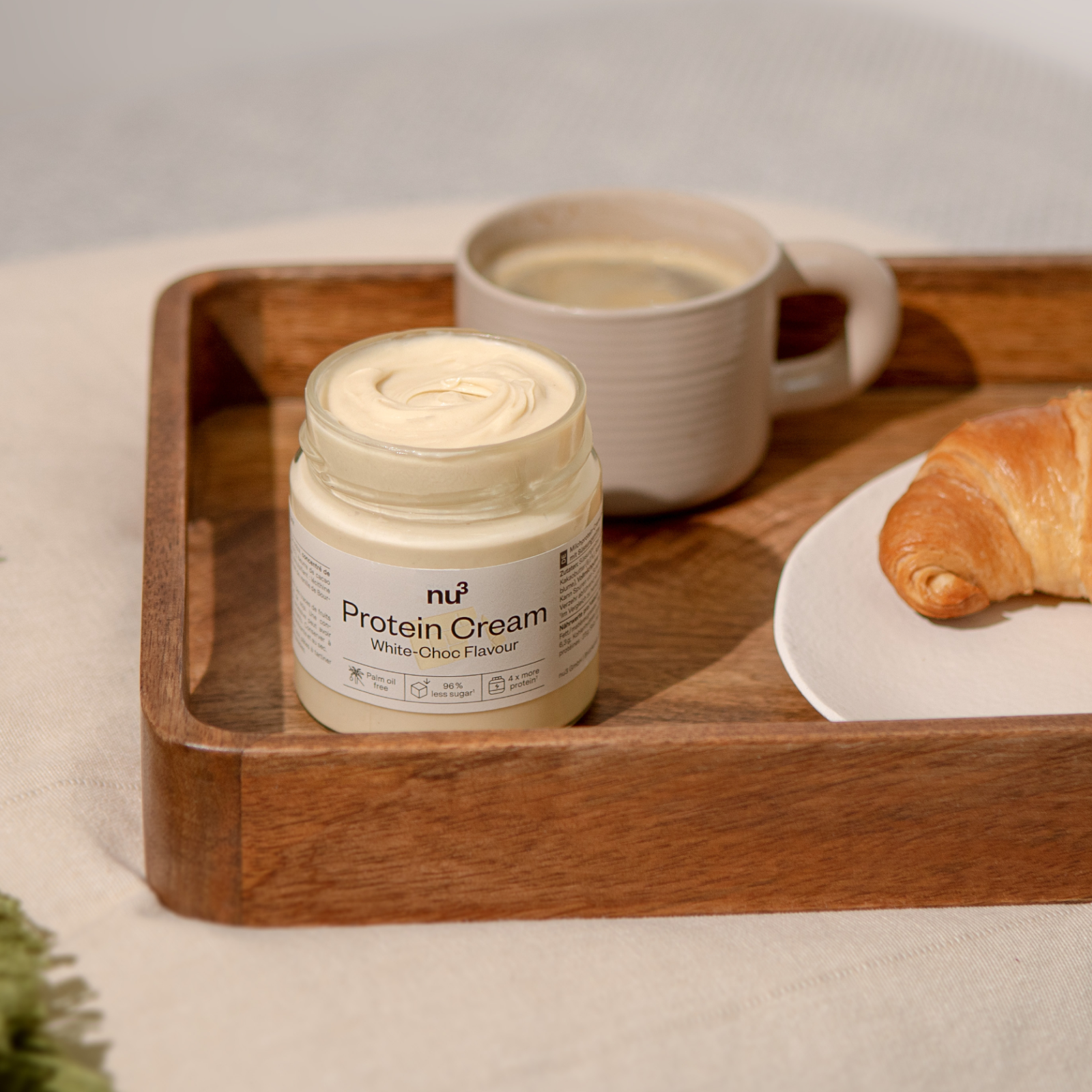 Frühstücks-Tablett mit Kaffee, Croissant und einem Glas nu3 Protein Cream White-Choc