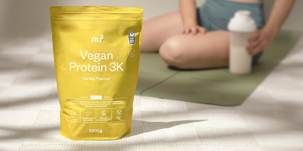 Vegan Protein 3K Vanille vor Sportlerin auf Fitnessmatte